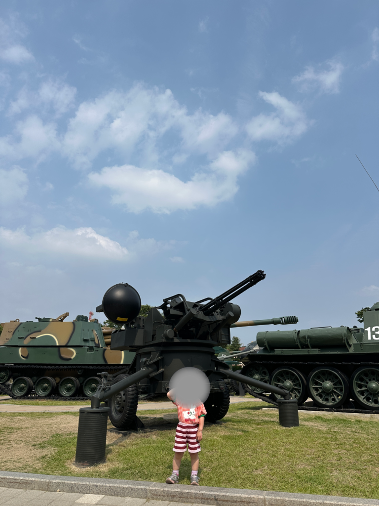 Child posing in front of military equipment at the War Memorial of Korea outdoor exhibition