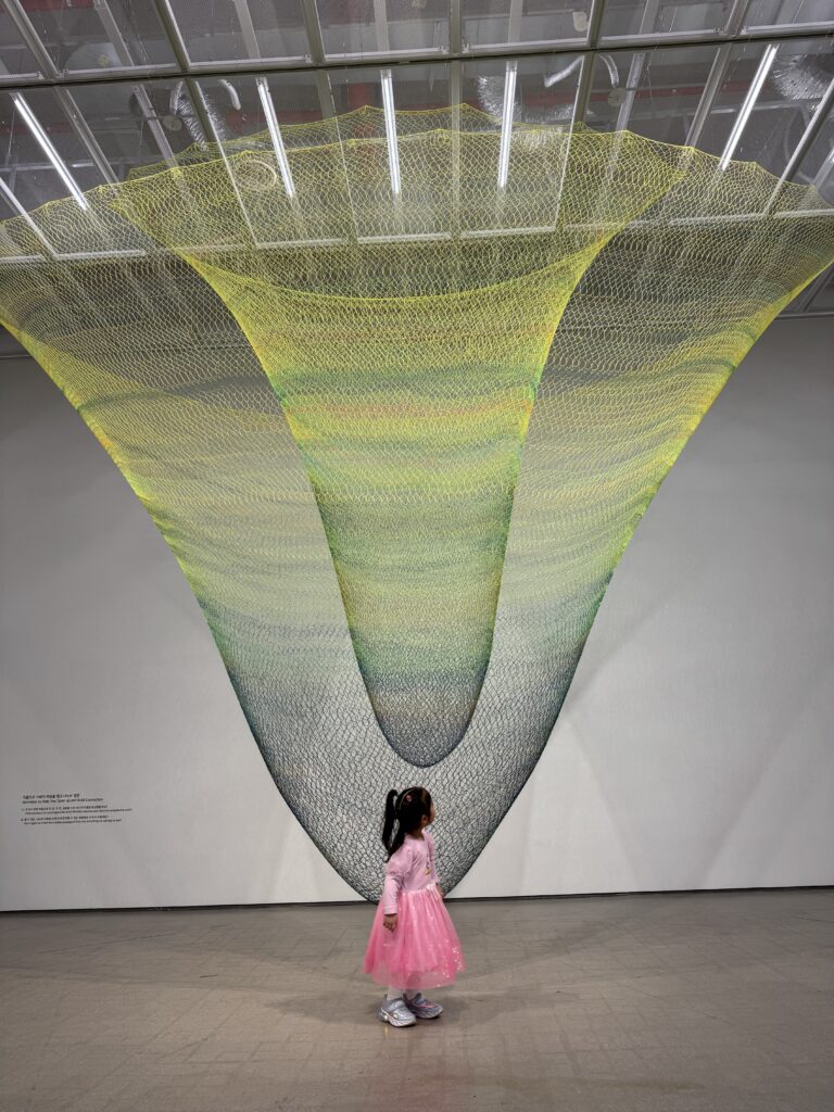A child looking up at a giant net installation artwork at MMCA Seoul