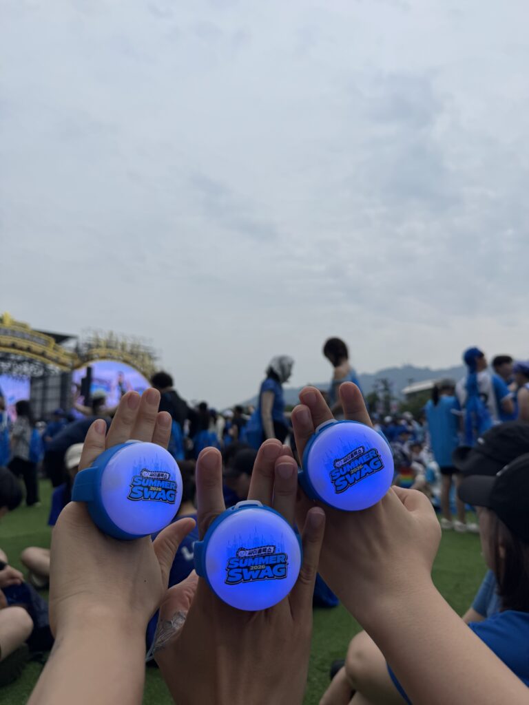 Summer Swag 2026 official light-up merchandise held up by fans.