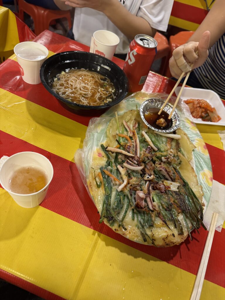 Korean seafood pancake (haemul pajeon), noodles, and drinks at a pojangmacha street food tent after PSY Summer Swag