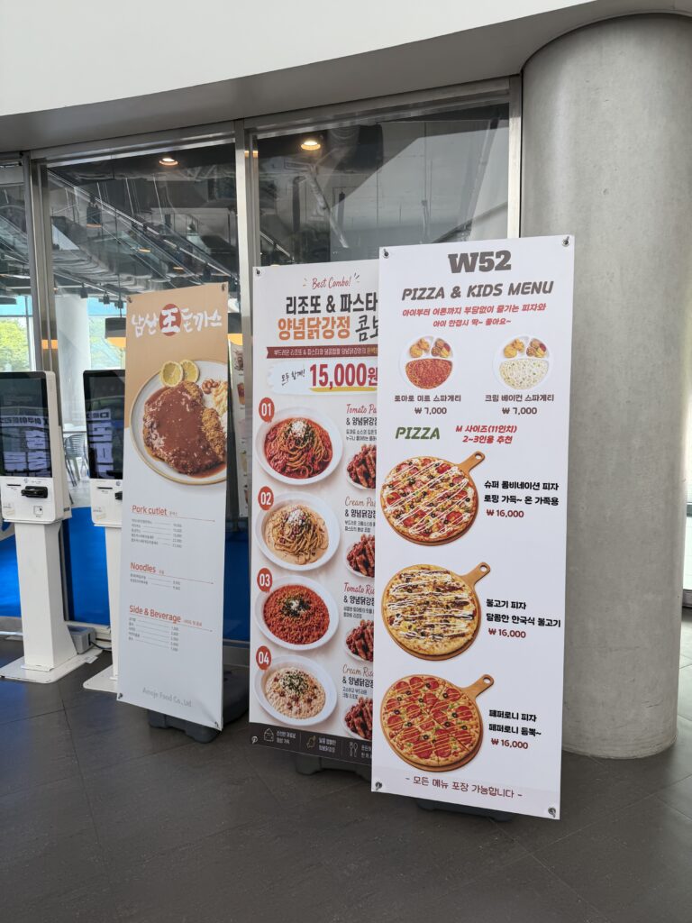 Restaurant menu boards at Aqua Planet Ilsan showing pork cutlet, pasta, and pizza with prices