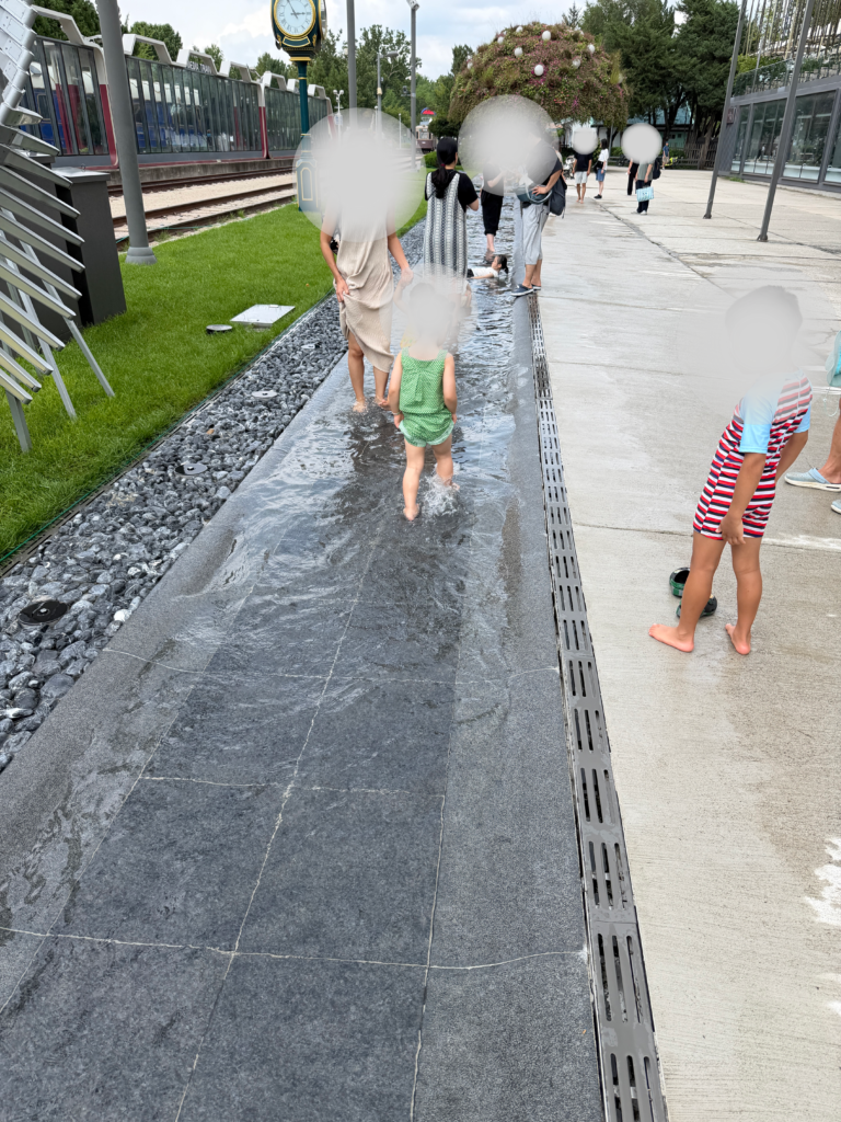 Children playing in a shallow water stream at Hwarangdae Railroad Park in summer