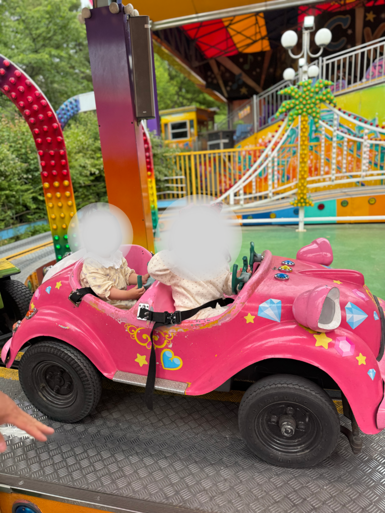 Two young children riding a pink toy car ride at Seoul Land