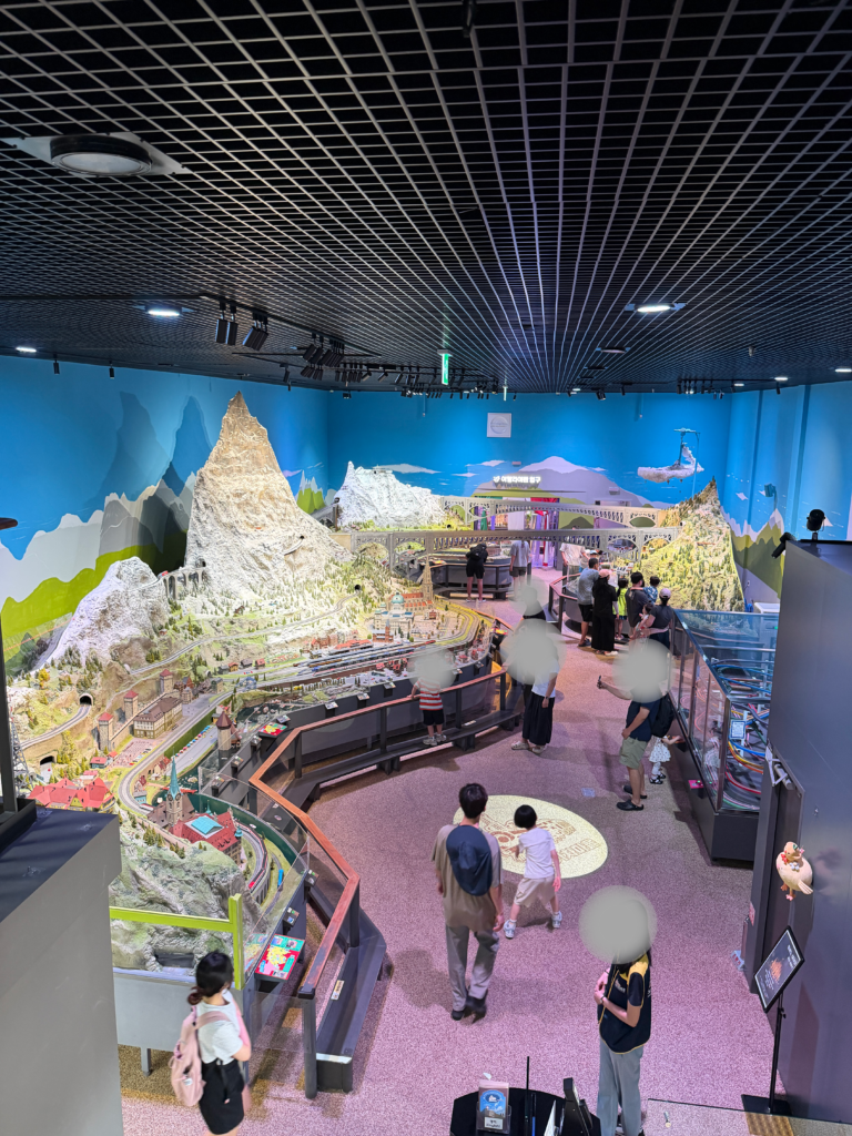 Wide interior view of the Swiss Hall showing the Matterhorn miniature and visitors, Nowon Train Village