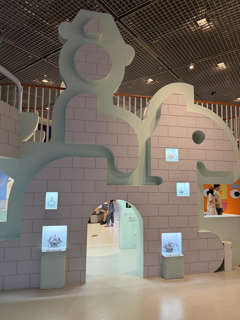 Mint-green cut-out wall shaped like a Korean artefact with archways and small display cases, Children's Museum Seoul