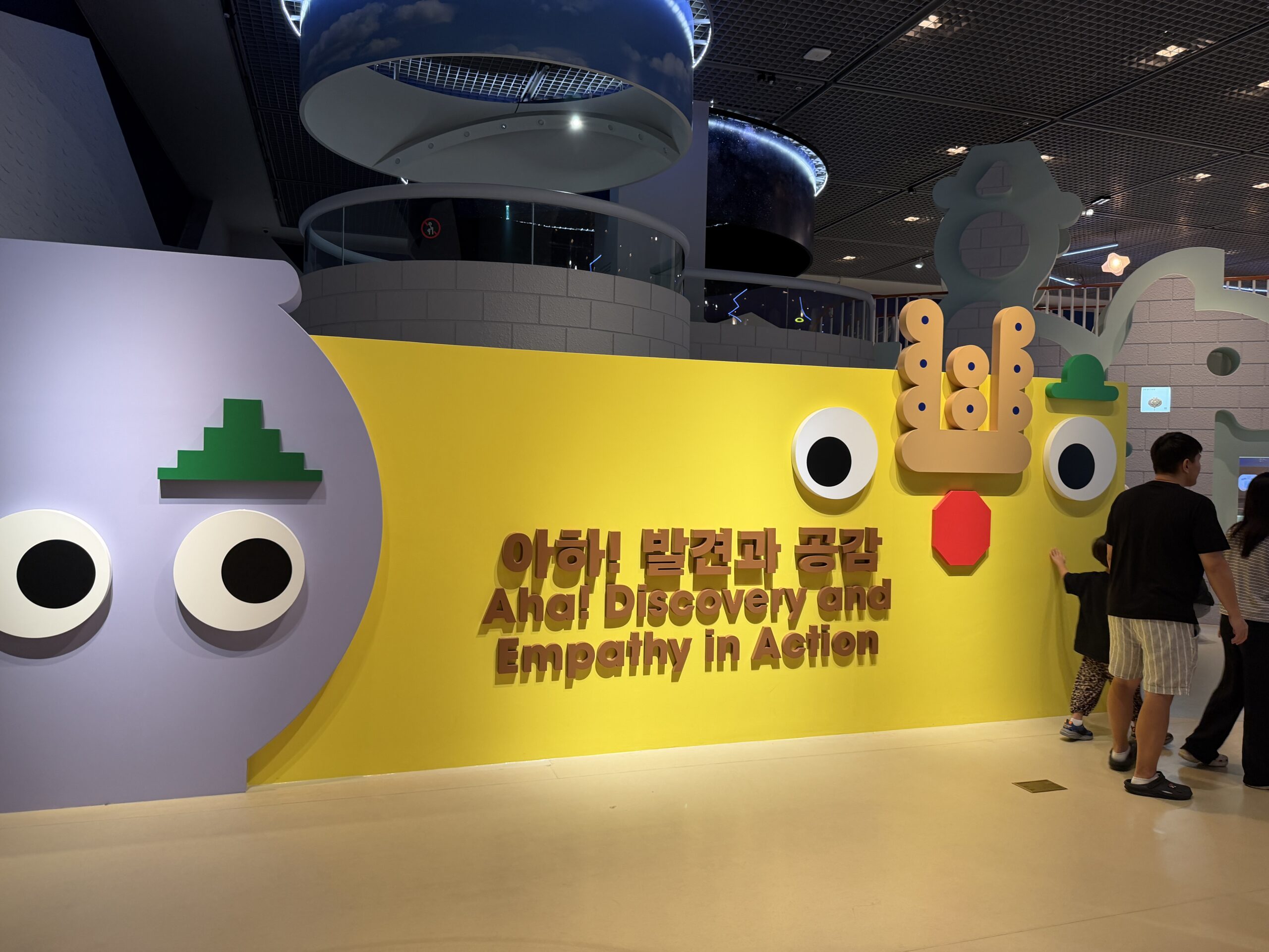 Yellow entrance wall with large eyes and the sign "Aha! Discovery and Empathy in Action" at the Children's Museum, Seoul