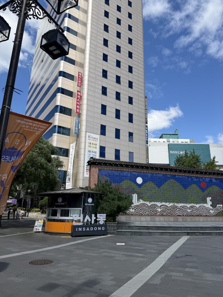 The INSADONG sign and tourist information kiosk at the entrance to Insadong Street with a tiled mural wall behind
