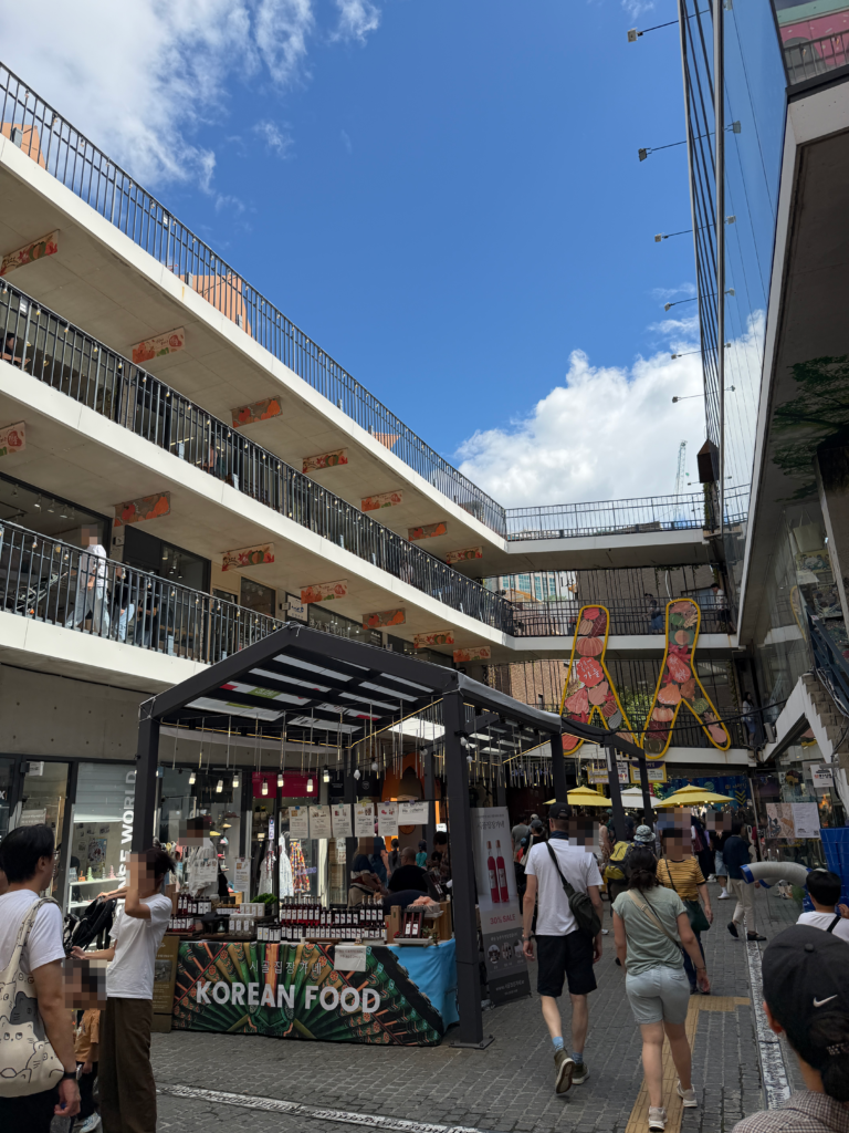 The central courtyard at Ssamzigil in Insadong with tiered shop balconies and a Korean food stall at ground level