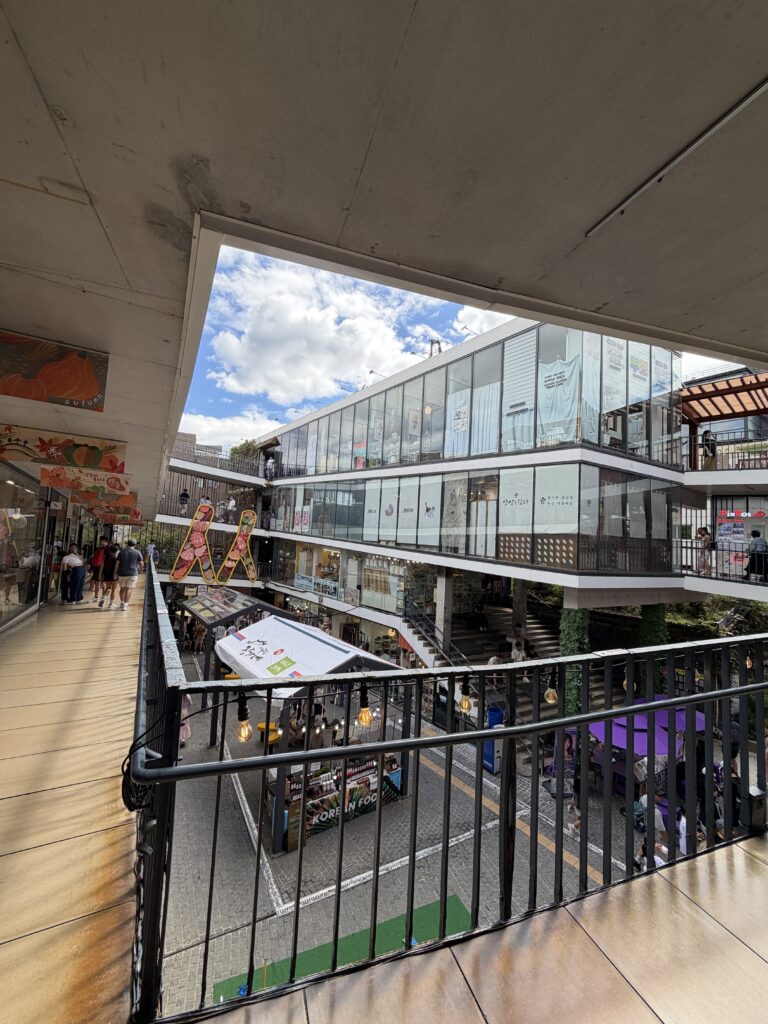 View down into the Ssamzigil courtyard from the sloping walkway on an upper level, with the ramp surface and railing in the foreground