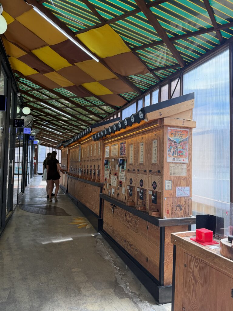 A covered corridor at Ssamzigil lined with wooden fortune-telling machines built to resemble traditional Korean shopfronts