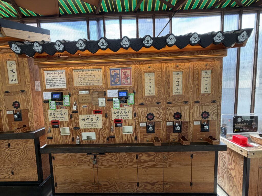  Close-up of a fortune-telling machine at Ssamzigil with a wooden mallet on a chain and a sign confirming card payment