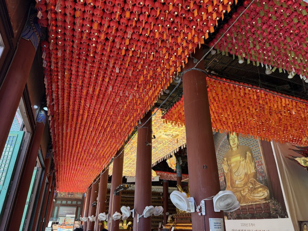 Ceiling of the main hall at Jogyesa Temple densely hung with thousands of red and orange prayer lanterns