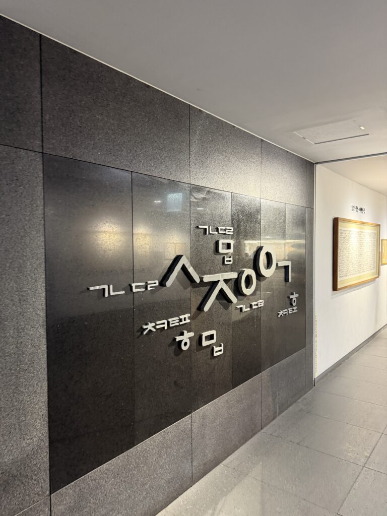 Hangul consonants and vowels mounted as three-dimensional shapes on a dark stone wall at The Story of King Sejong